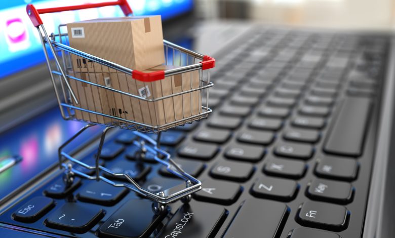 E-commerce. Shopping cart with cardboard boxes on laptop.